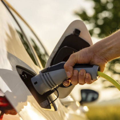 Photo of a person plugging in their electric vehicle to charge. EV, electric vehicle, charge, charging station, electrification, energy transition